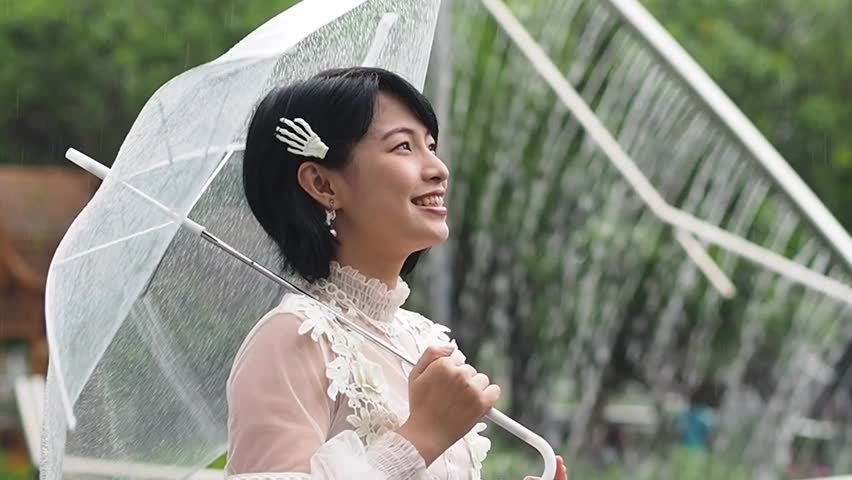 Happy young Asian woman in rainy day,slow motion shot.
