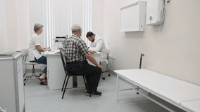 Elderly man in office at doctor's appointment. Clip. Patient at doctor's appointment with nurse in modern clinic. Elderly man complains of ailments at doctor's appointment
