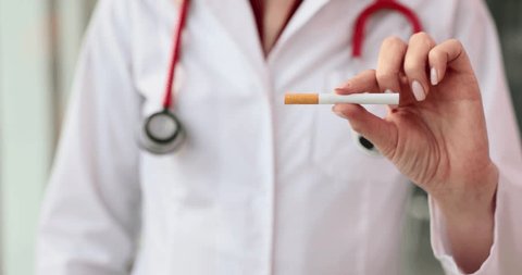 Doctor shows stop gesture and holds cigarette. Smoking cessation and health concept Video Stok