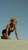 African sportive woman doing push-ups outdoors in a sunny day