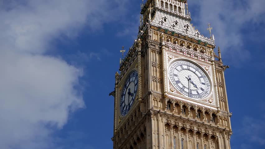 Low-angle shot of Big Ben clock tower on sunny day with beautiful clouds passing by following restoration. British cultural icon. Tourist destination landmark in London, United Kingdom.