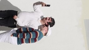Caucasian gay couple doing a selfie on an empty wall, vertical. Concept of homosexual relationship