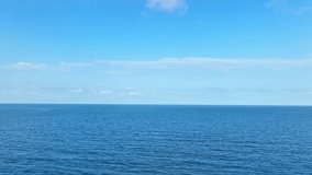 Unending waves cascade upon the tranquil sea, as a drone glides effortlessly, framing the serene tableau of blue seas and skies. Stock footage. Loop of sea background. 4K.
