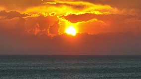 Golden sunbeams kiss the rippling ocean, blending with hues of orange and red, creating a mesmerizing spectacle that stretches infinitely into the horizon. Cinematic footage. sunset sea background.
