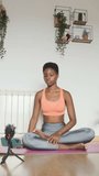 African woman stretching while filming an online class with a mobile