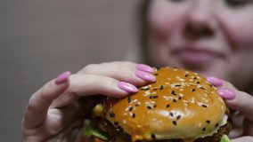 Tidbit, Cheeseburger in the arms of a smiling Caucasian woman whose face is out of focus. fast food concert, unhealthy diet