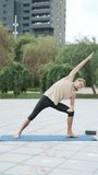 Man exercising on a mat while doing yoga outdoors in a park.
