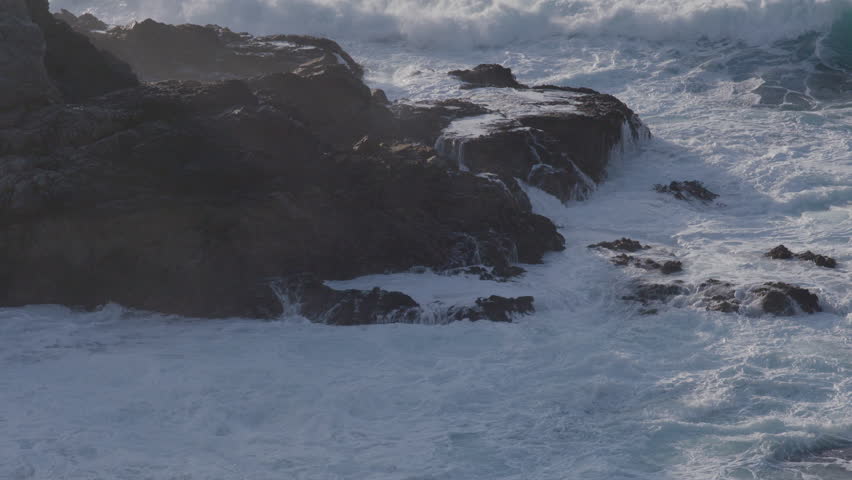 Stationary shot of waves crashing against the massive boulder on a Big Sur California Beach. Royalty-Free Stock Footage #3449623921