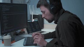 Young male software developer with headsets working, typing on the keyboard and looking focused at the screen. Computer programmer in the headphones is working hard. Developers programming codes.  - Powered by Shutterstock - Get 15% off with code: PIKWIZARD15