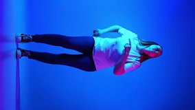 Happy, positive woman in casual outfit dancing against gradient blue studio background in neon light. Concept of beauty and fashion, self-expression, human emotions. Vertical orientation. Ad