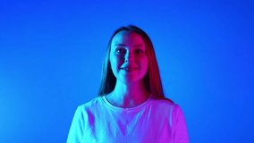 Success. Young emotional woman looking at camera in neon light against blue gradient studio background. Concept of beauty and fashion, self-expression, human emotions, success, happiness. Ad