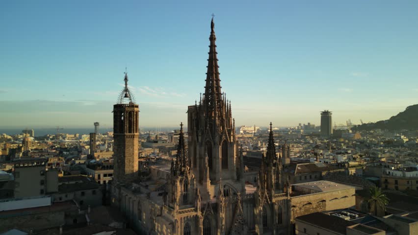 Aerial video goes up over the streets of Barcelona towards the Barcelona Cathedral. A famous historic Gothic landmark in the Old City district. Aerial panoramic view of the city. Barcelona, Spain Royalty-Free Stock Footage #3449725943