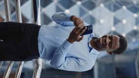 Vertical Video. African American Businessman Scrolling the Catalog with the Products while Standing Outside near the Business Centre. Positive Guy Using Smartphone Outside. People and Technology - Powered by Shutterstock - Get 15% off with code: PIKWIZARD15