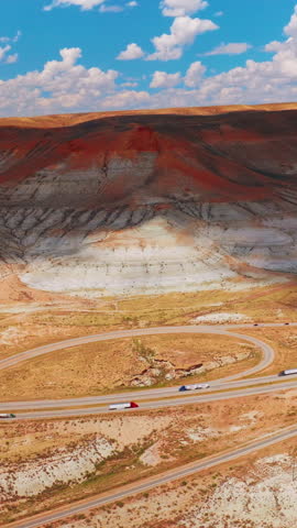 Highway in Wyoming going through the mountain. Little town hiding in the bare rocks. Aerial view. Vertical video.
