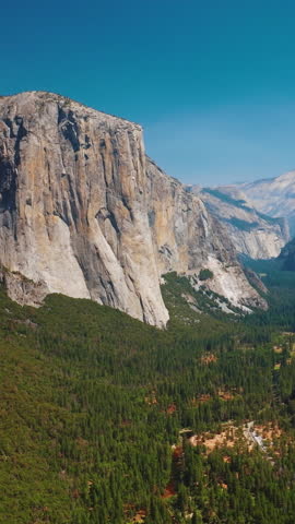 Enormous steep rocks in Yosemite National Park, California, USA. Green pine tree forests growing between the cliffs. Sunny day footage. Vertical video. Royalty-Free Stock Footage #3449766671