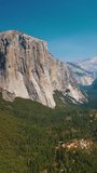 Enormous steep rocks in Yosemite National Park, California, USA. Green pine tree forests growing between the cliffs. Sunny day footage. Vertical video.