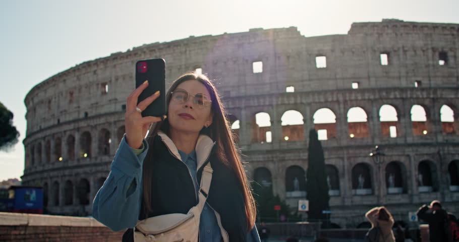 A beautiful woman tourist takes a selfie near the Coliseum. Happy moments of travel photo for memory near ancient roman architecture in rome italy. High quality 4k footage