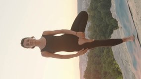 Vertical video of Caucasian happy woman training meditation on yoga mat. Positive female standing on one hand and holding arms together while looking at camera. Body balance. Harmony concept.