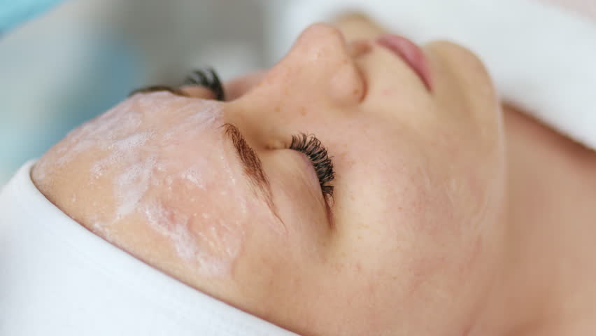 Beautician cosmetologist applies cosmetic product gel bubble acid peeling mask on face. Skincare and cosmetology spa concept.