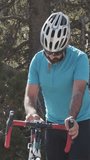 Vertical video of Male cyclist looking at the cycle computer of his road bike in the mountain.