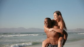 Camera tracks up shot of loving young couple in swimwear with man giving woman piggyback running along beach in South Africa - shot in slow motion - Powered by Shutterstock - Get 15% off with code: PIKWIZARD15