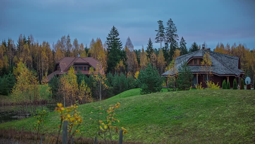 Timelapse shot of wooden cottages by the side of a lake on a beautiful autumn day.