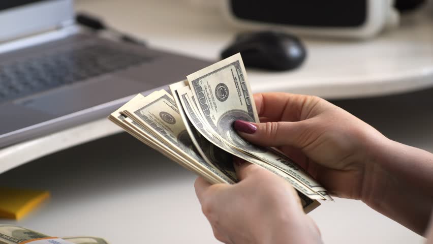 close-up of female hands counting a stack of hundred-dollar US banknotes. a businesswoman is counting cash. the concept of investment, money exchange, bribes or corruption. 4K