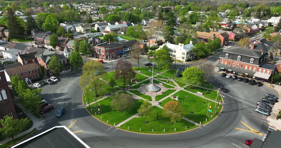 Town in USA with American flag waving in breeze. Historic rising aerial reveal shot during daytime.