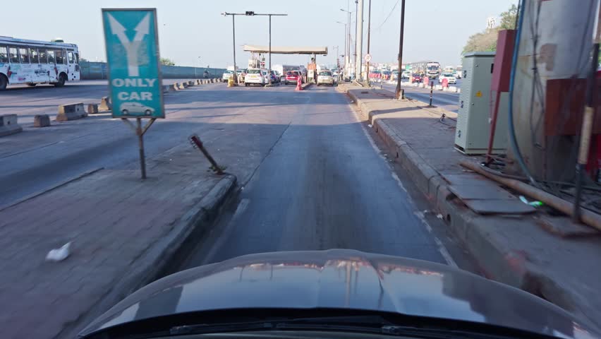 Busy urban street scene with cars and a toll booth under a clear sky car driving Asia india