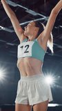 Vertical Video. Portrait of Professional Female Athlete Happily Jumping Celebrating New Record on a Sport Championship. Determined Successful Sportswoman Raising Arms after Winning Gold Medal