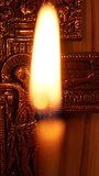 A Christian cross and a burning candle. Close-up of a cross with a crucifixion. The concept of human faith in God. Vertical video for shorts.
