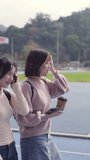 Vertical video of two young Taiwanese female college students sitting happily talking on a university campus in Taipei, Taiwan