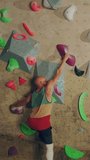 Vertical Portrait of Strong Experienced Rock Climber Practicing Solo Climbing on Bouldering Wall in a Gym. Man Exercising at Indoor Fitness Facility, Doing Extreme Sport Lifestyle Training