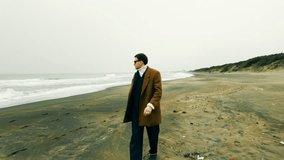 Charming well dressed Italian model actor ready for film scene during film production walks on the beach on a cloudy day and smiles looking at the camera. - Powered by Shutterstock - Get 15% off with code: PIKWIZARD15