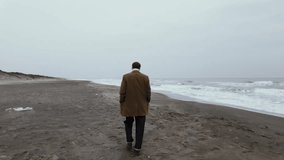 Charming well dressed Italian model actor ready for film scene during film production walks on the beach on a cloudy day and smiles looking at the camera. - Powered by Shutterstock - Get 15% off with code: PIKWIZARD15