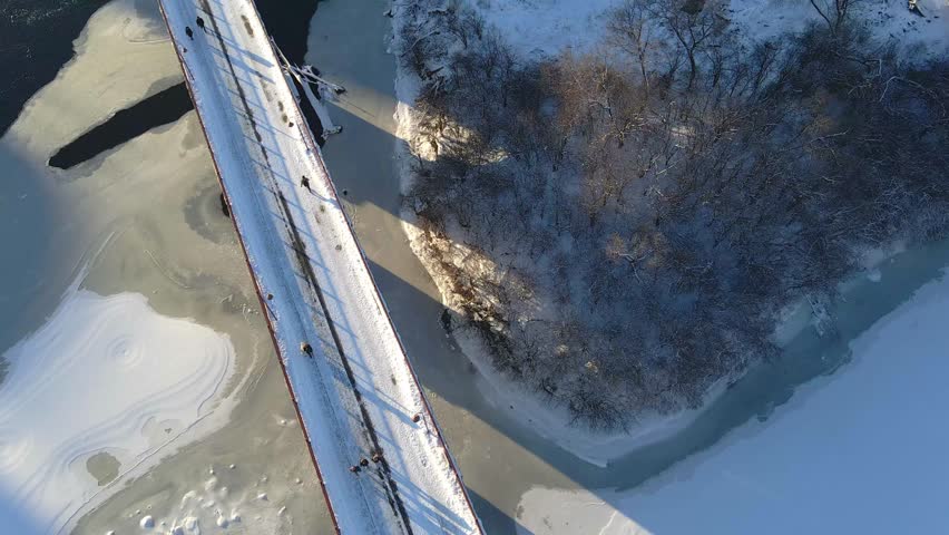 Aerial view of people at stone arch bridge crossing the mississippi river in Minneapolis winter afternoon ice formations