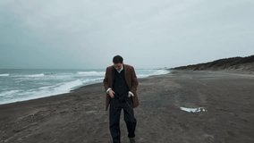 Fascinating Italian model actor well dressed ready for the cinema scene during the production a movie walks on the beach on a gray day and smiles looking at the video camera. - Powered by Shutterstock - Get 15% off with code: PIKWIZARD15