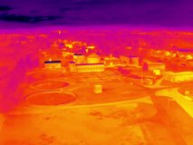 Aerial infrared thermal view of wastewater treatment plant with sedimentation tanks, in purple and yellow hues