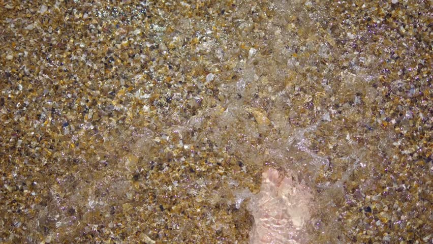 Barefoot person walking on the beach with waves washing over feet in 4k slow motion 120fps