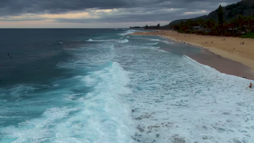 Aerial view of waves crashing over surfers at Ehukai Beach Park shore, Ohau. Hawaii Royalty-Free Stock Footage #3450128417