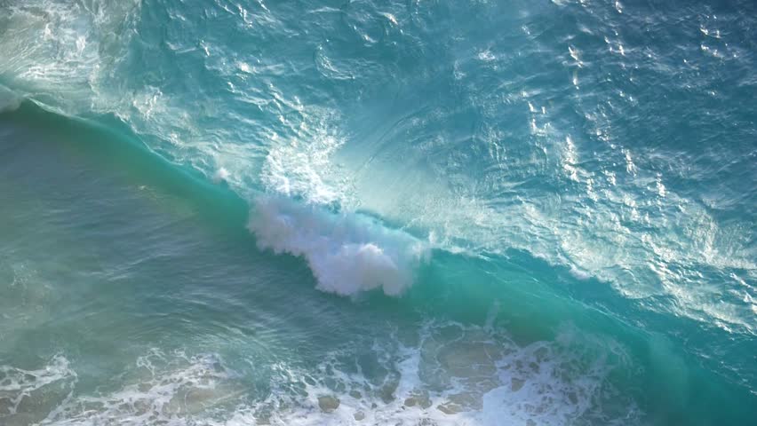 Slow motion clip of a blue ocean wave crashing on a beach Royalty-Free Stock Footage #3450138691