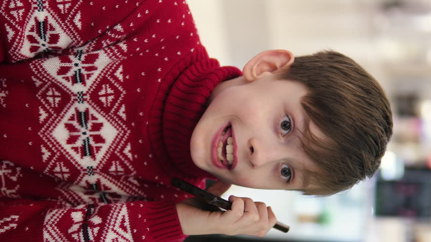 Christmas shopping, Caucasian boy talking on the phone in a shopping center. Sale conversations, Teenager in a shopping center against the backdrop of the holiday bustle.vertical video
