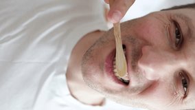 Vertical video. Young man brushing teeth in bathroom. Guy cleaning mouth doing morning dental care routine. Caucasian man using natural bamboo eco brush. - Powered by Shutterstock - Get 15% off with code: PIKWIZARD15