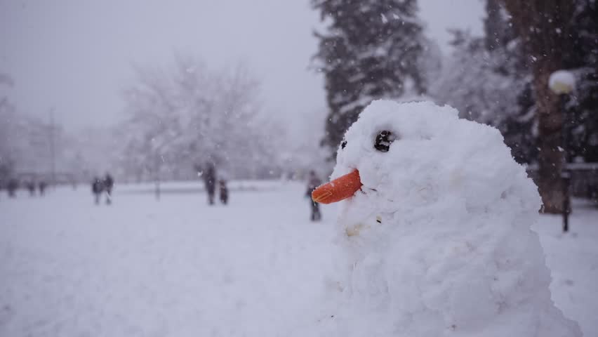 close up of a snowman in the park while it is snowing heavily and people at the background, Athens snowstorm Royalty-Free Stock Footage #3450226245