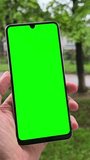 Man holding a phone in hands with green screen. Smartphone green screen background.