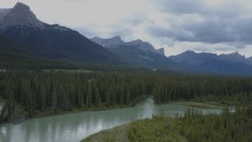 Drone point of view flying over the river and pine tree forest, view on Canadian rockies in Alberta. Mountain landscape nature environment conservation no people travel concept