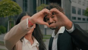 Two business people co-workers in love kind volunteers smiling happy partners Indian couple Arabian man businessman woman businesswoman colleagues showing heart shape with hands at camera in city love - Powered by Shutterstock - Get 15% off with code: PIKWIZARD15