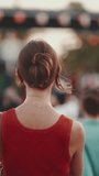 VERTICAL VIDEO: Close-up, girl stands on the square and looks around in downtown. Closeup of young woman is standing in the city center looking around at the crowd of people in the evening