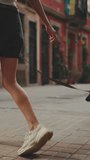 VERTICAL VIDEO: Girl walks down the city street with her pet. Only the legs of walking girl