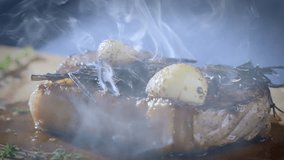 Hot smoking steak on a wooden cutting board. Meat fresh from the pan. Fried meat with garlic and rosemary. Food preparation. Slow motion 100fps 4k video. High quality 4k footage